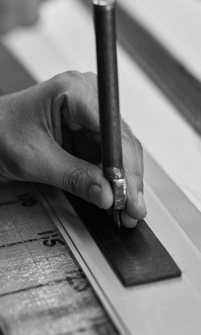 Leather worker marking out belt straps on a full-grain hide in the workshop